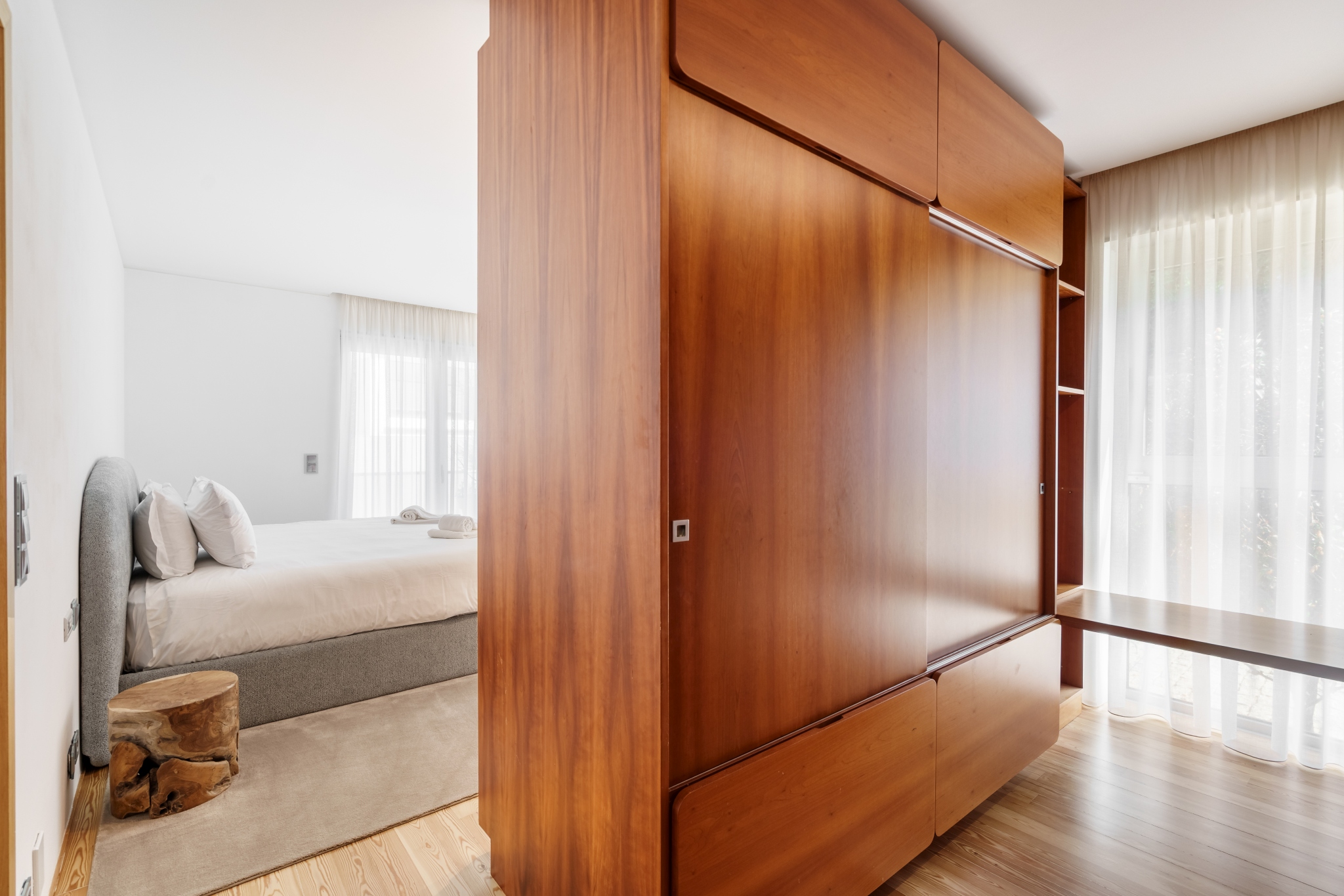 Courtyard Room — cherry-wood wardrobe partition beside the bed.