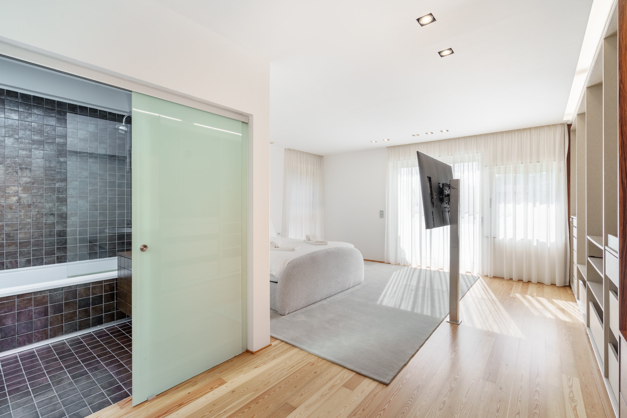 Garden Suite — ensuite rain shower in dark stone behind a frosted sliding door.