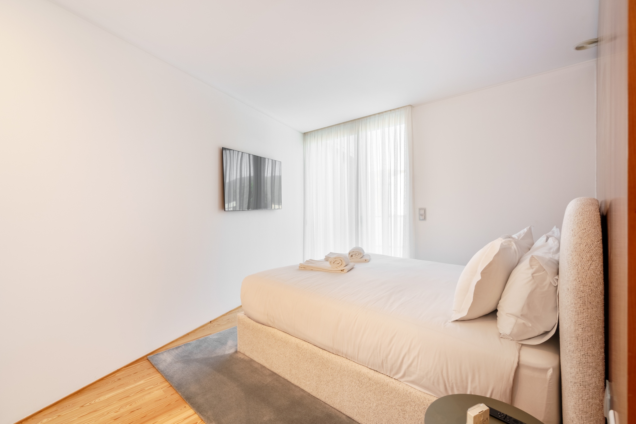 Quiet Suite — king bed, wall-mounted television, tall sheer-curtained window.