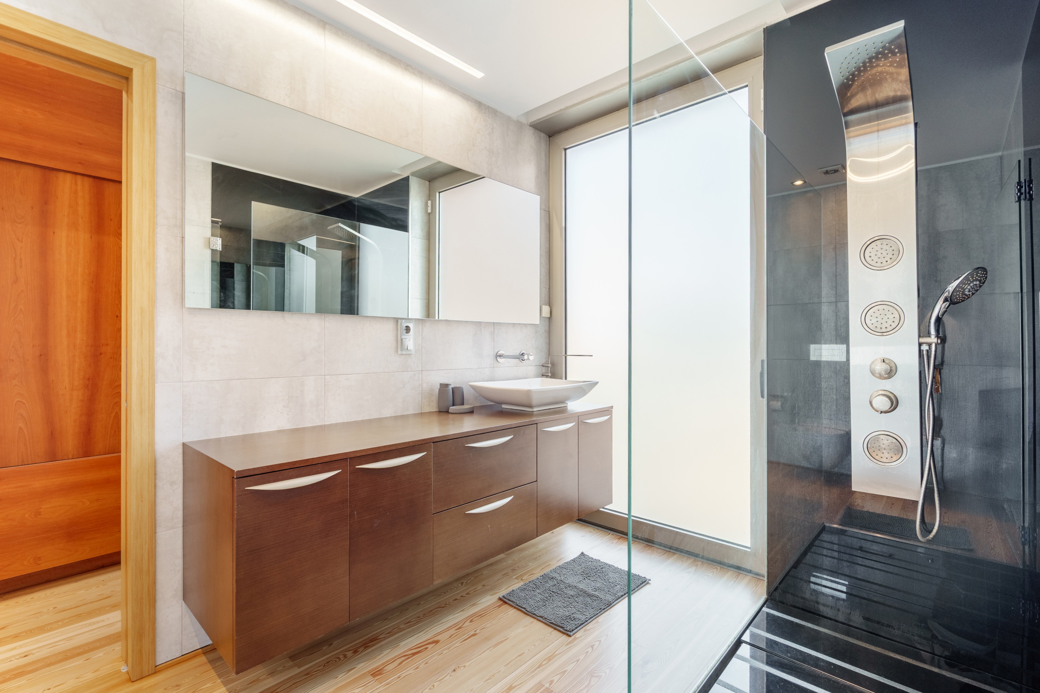 Quiet Suite — ensuite with a multi-jet shower column behind frosted glass.