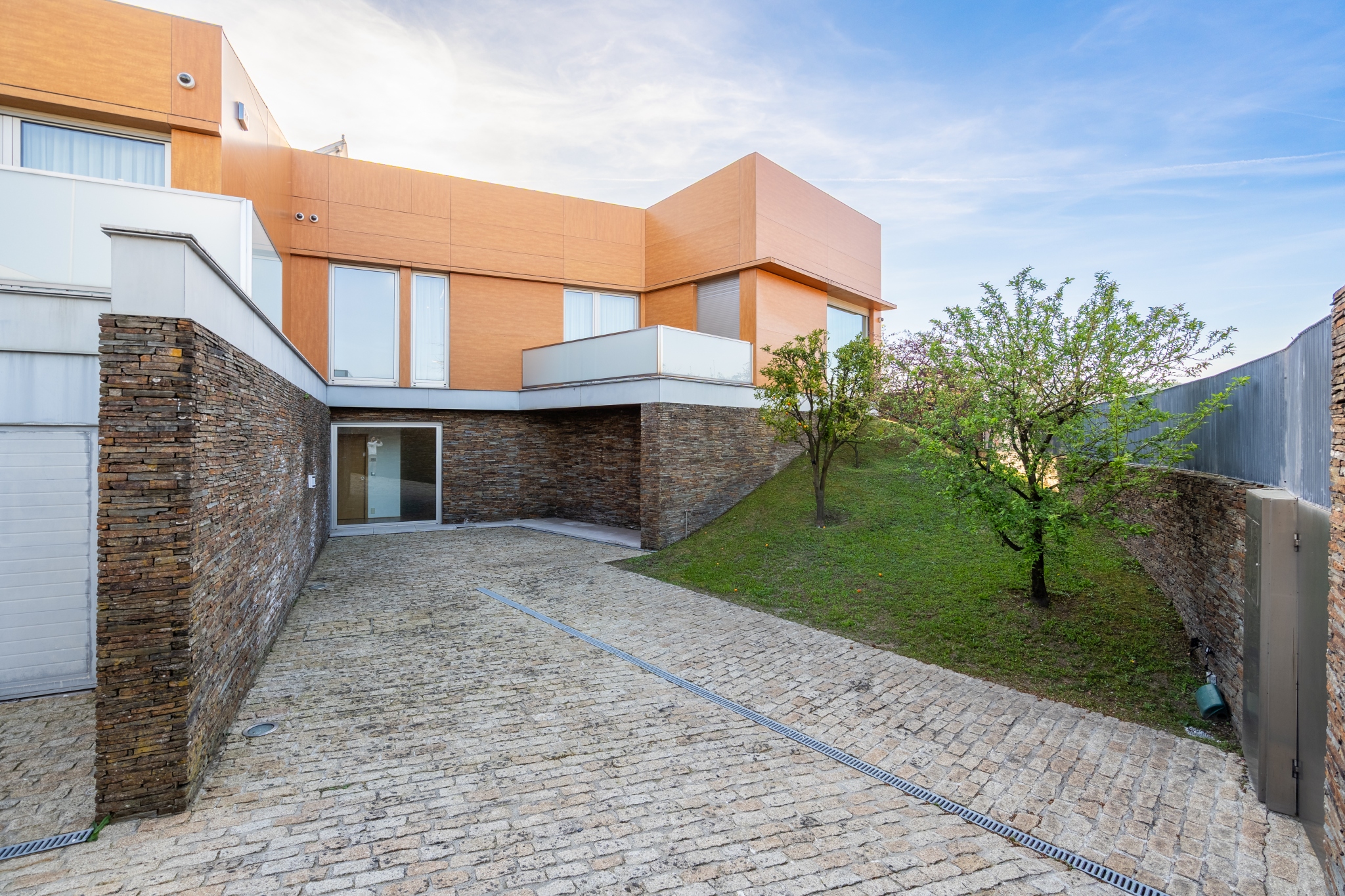 The villa from the courtyard — wood-clad façade and walled garden.
