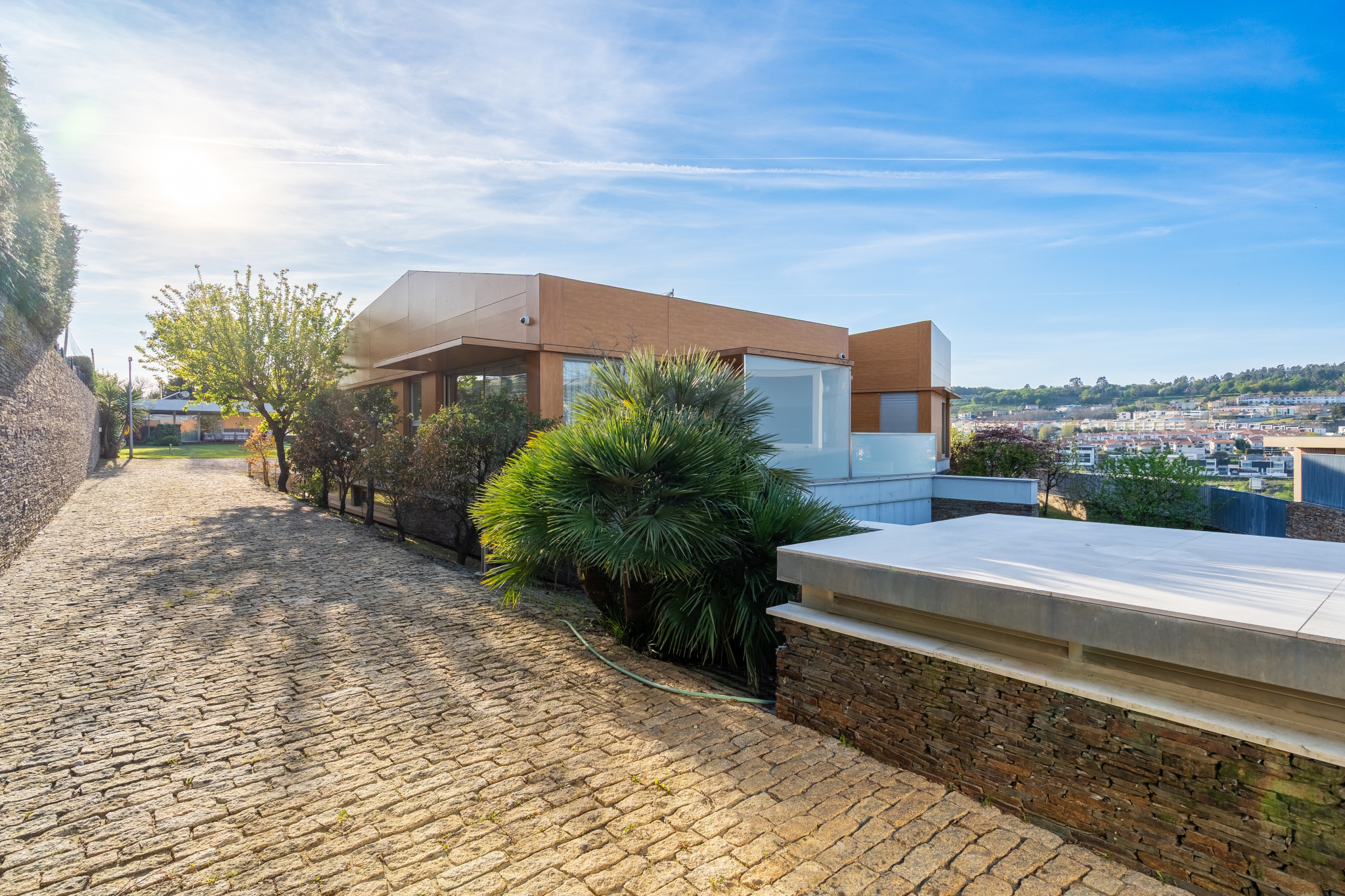 The villa's wood-clad façade above the cobblestone drive, the Braga valley beyond.