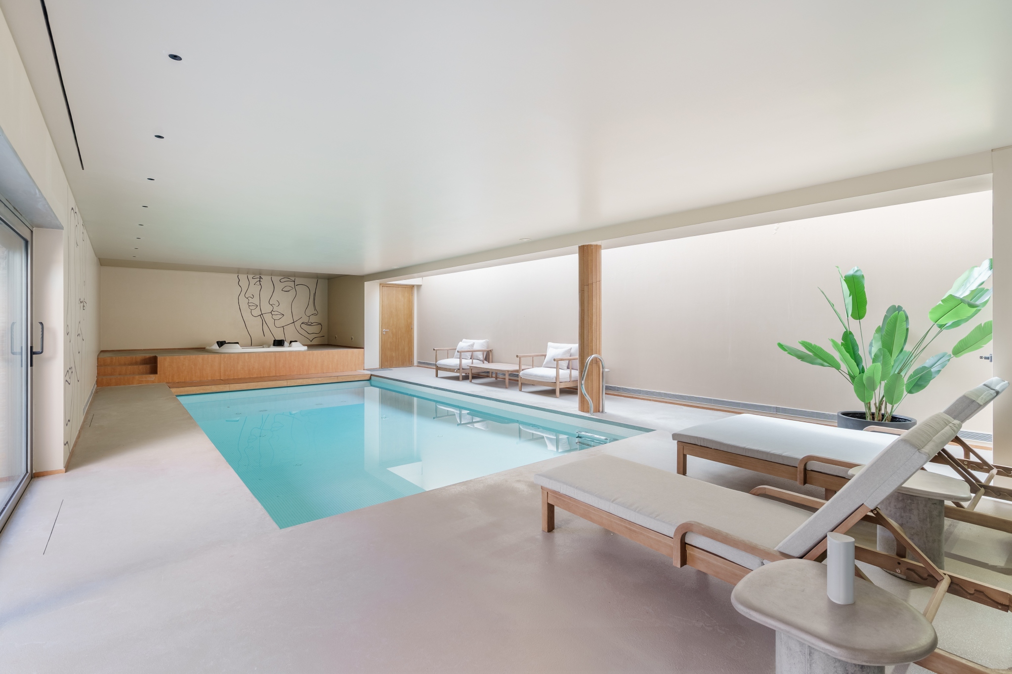 Indoor heated pool with a line-drawing mural and pale wood bench.