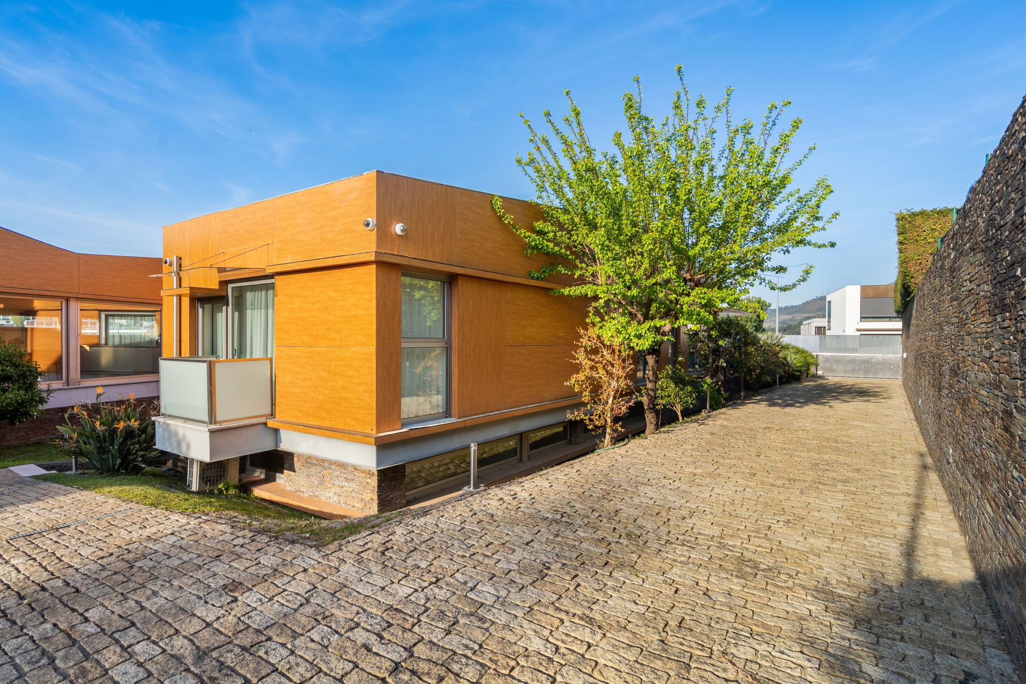 A rear corner of the villa, the orange wood cladding under late sun.
